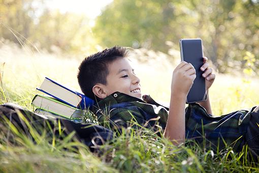 Boy reading a book on a tablet